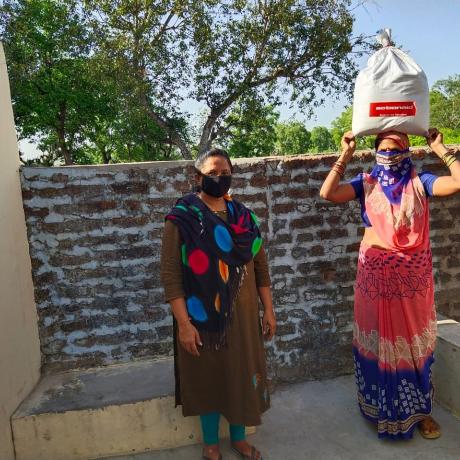 Women in India carrying a package of Covid-19 aid