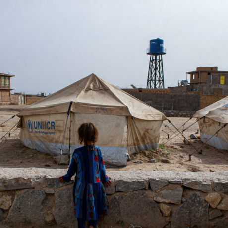 A little girl looks out across an IDP camp in Afghanistan