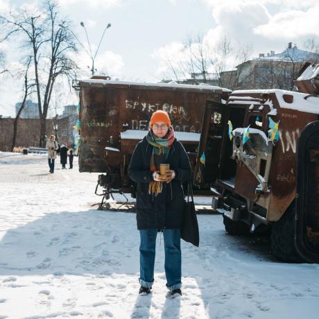 Olena, a Ukranian humanitarian worker poses in front of a snowy industrial background in Kharkiv